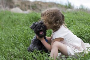 Czarny terier jako pies terapeutyczny – możliwości i wyzwania 14 little-girl-kissing-pet-dog-on-grass-field-2024-06-20-20-56-34-utc